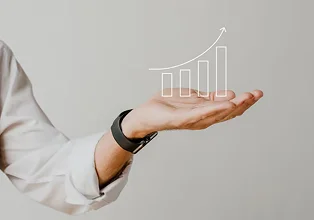 Hand presenting a rising bar graph symbolizing financial growth and operational efficiency, relevant to finance outsourcing benefits for businesses.